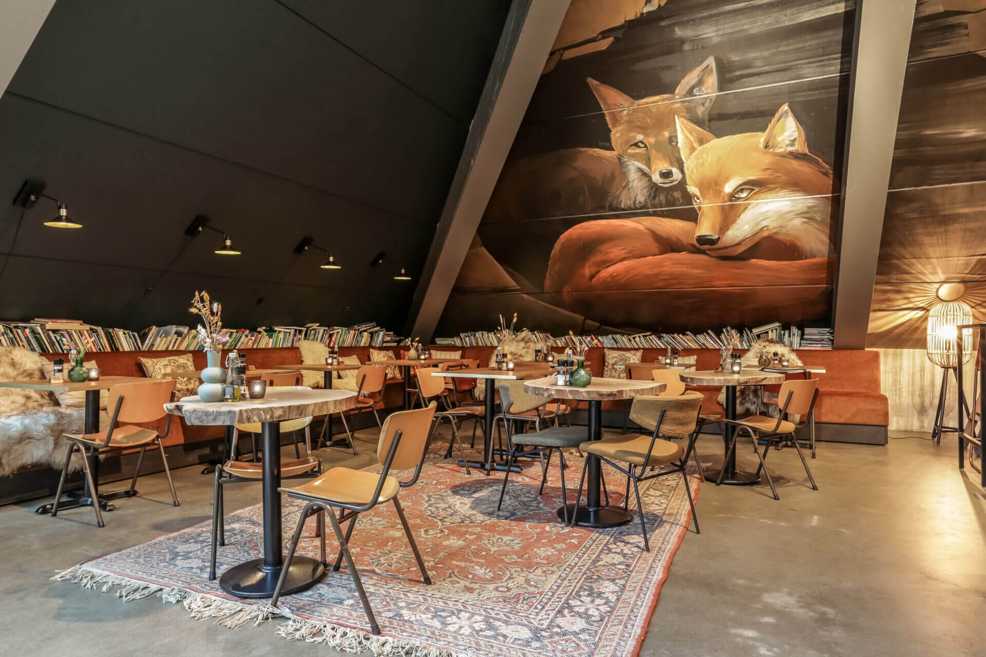 Restaurant with tables and chairs and slanted ceiling with fox on the wallpaper