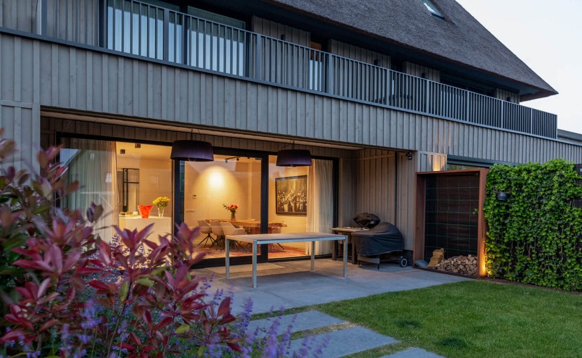 Backside of modern home with dinging room lit up inside