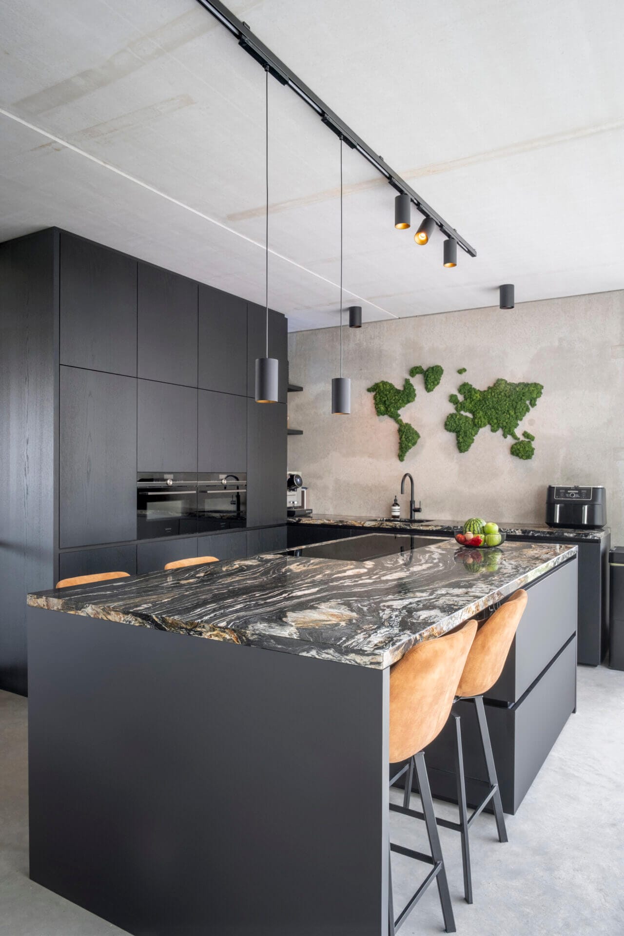 Kitchen with dark cabinets and dark marble countertop.
