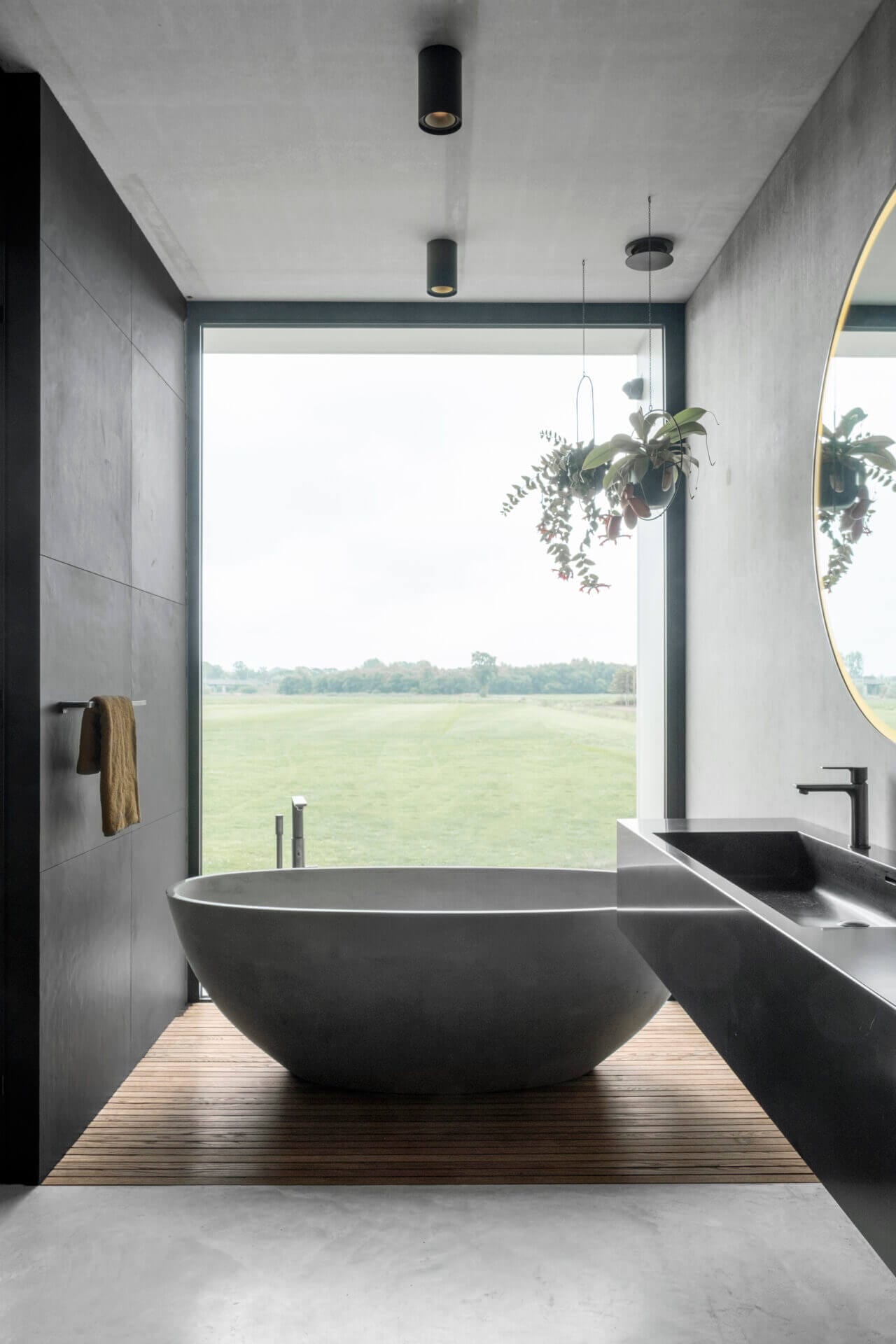 Bathtub with large window with a view over meadow.