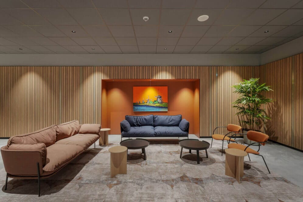 Couches and a orange wall with wooden panels on the sides