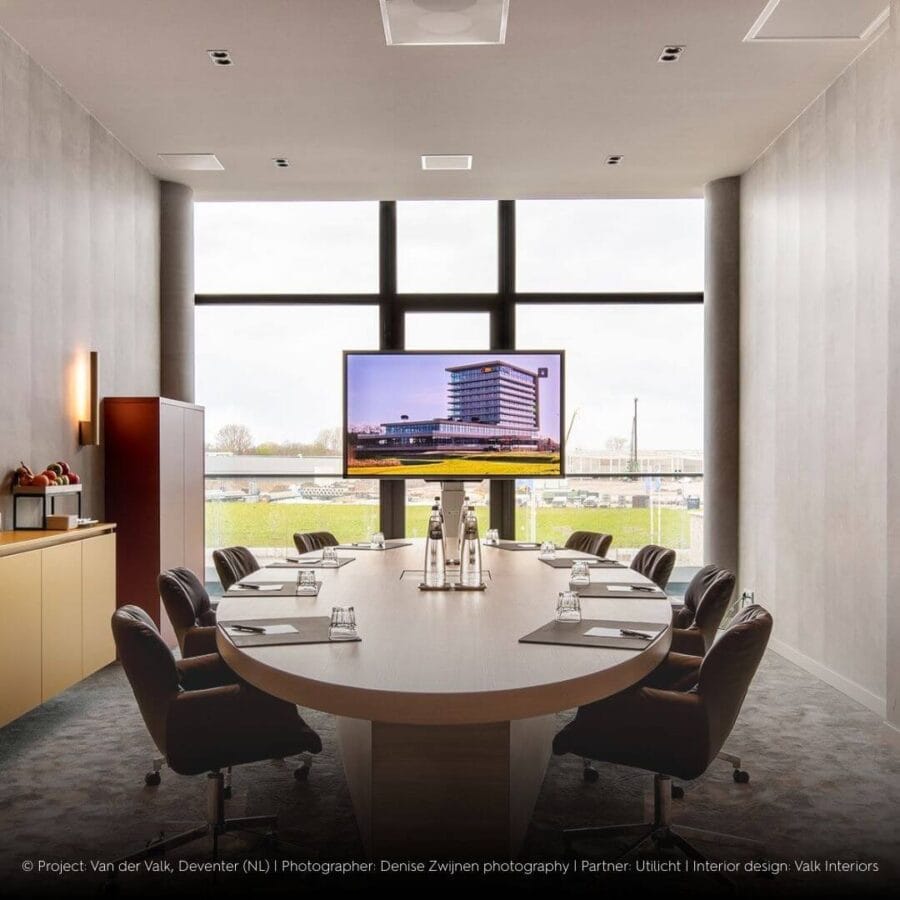 Oval table in modern office with big windows and black Dea Ceres M duo in the ceiling.