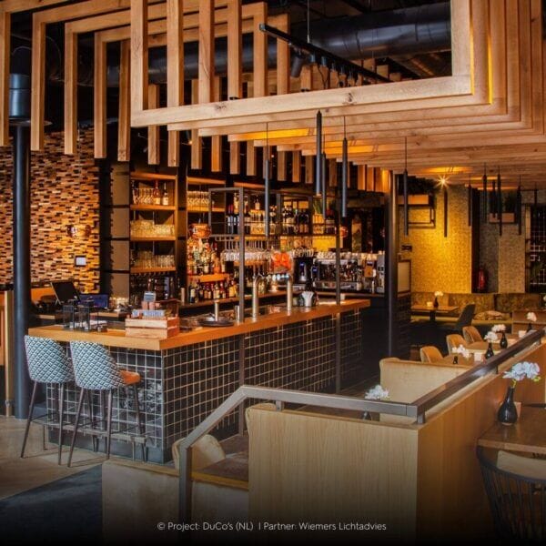 Restaurant with wooden elements and tube shaped Perla luminaires.
