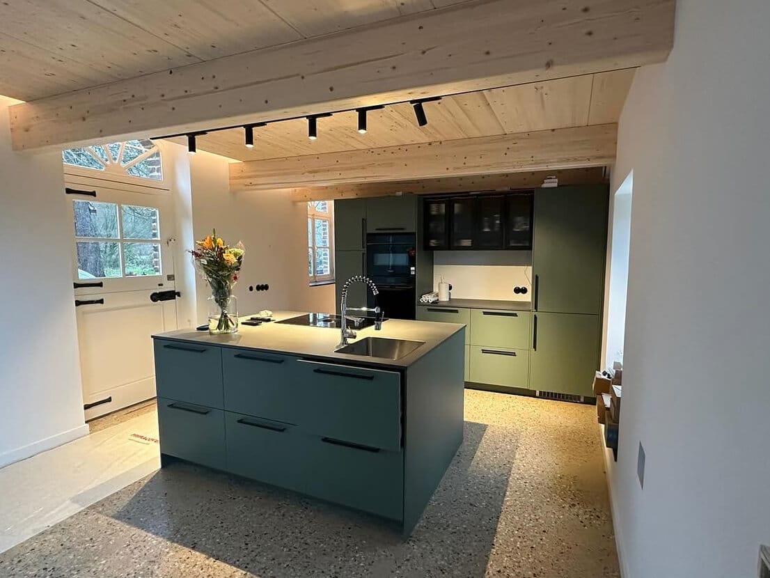 Green modern kitchen with black accents and black track lighting