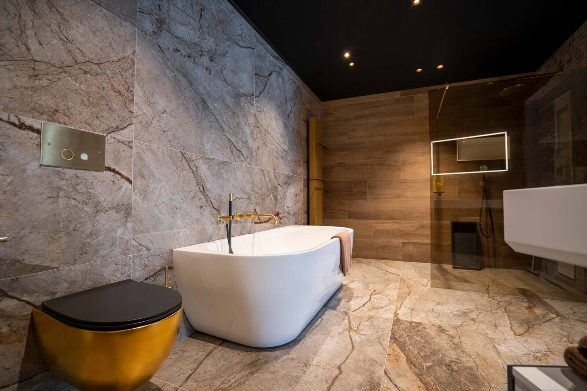 Luxurious modern bathroom with concrete colored walls with marble effect black ceiling with Dea Ceres with gold reflector.