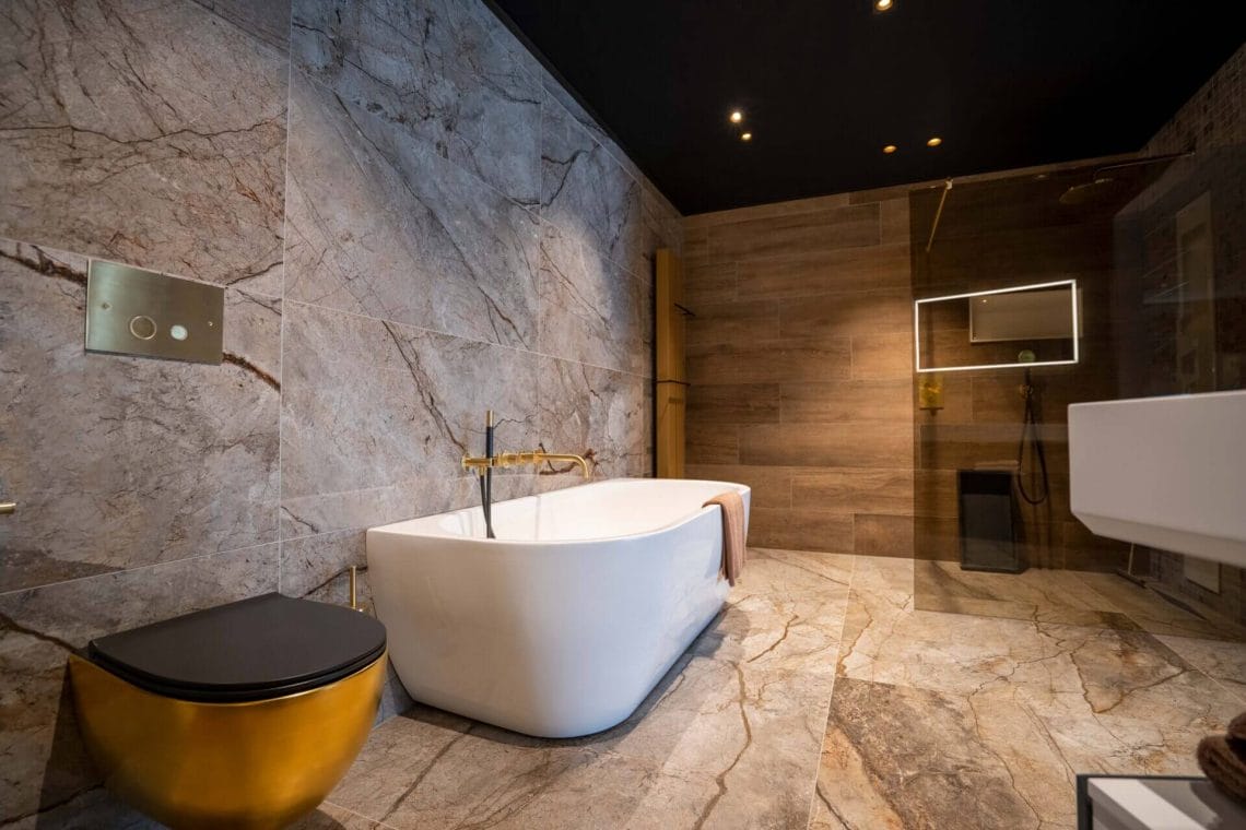 Luxurious modern bathroom with concrete colored walls with marble effect black ceiling with Dea Ceres with gold reflector.